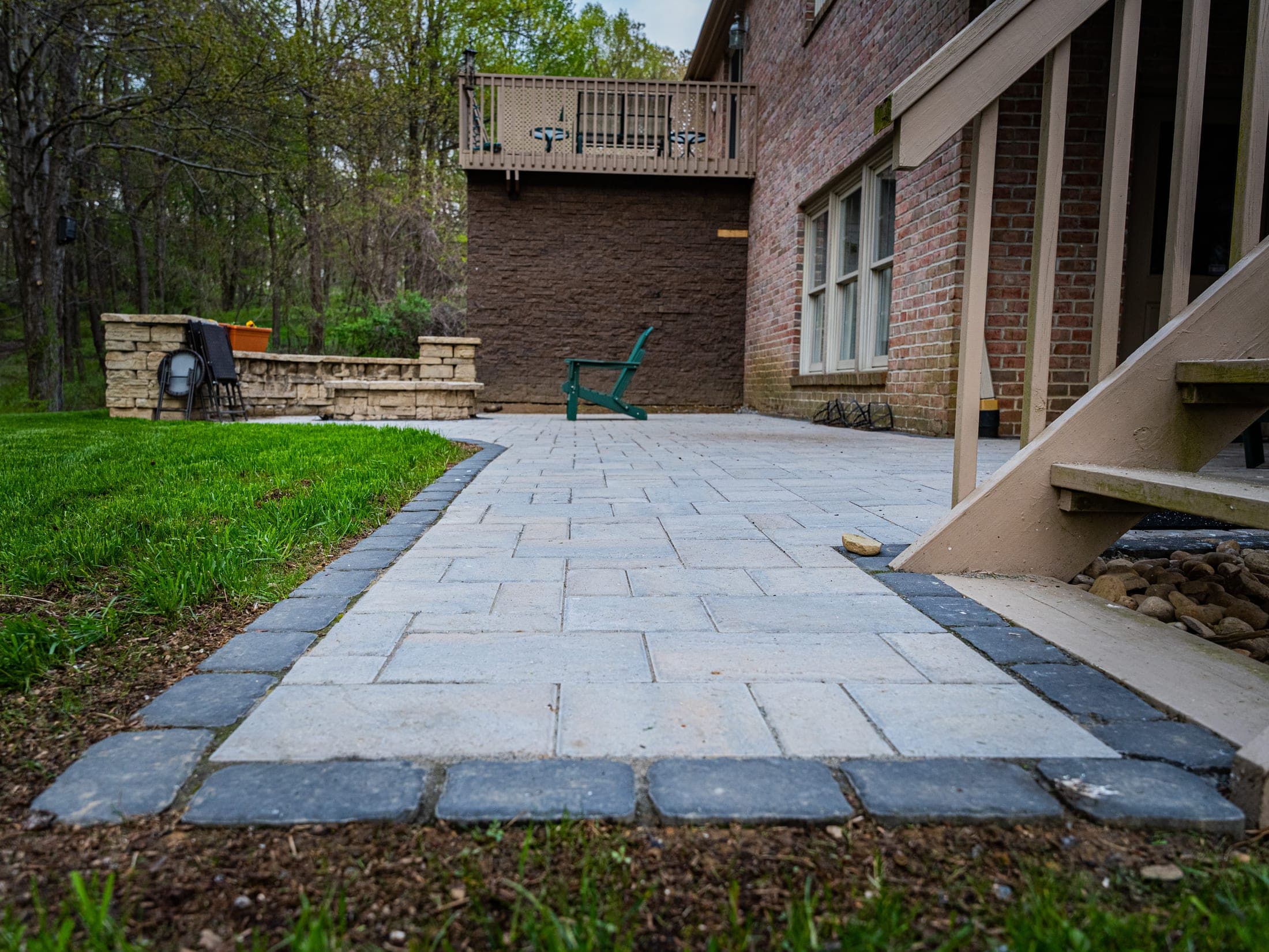 Paver patio and stone seat wall across the back of a brick home