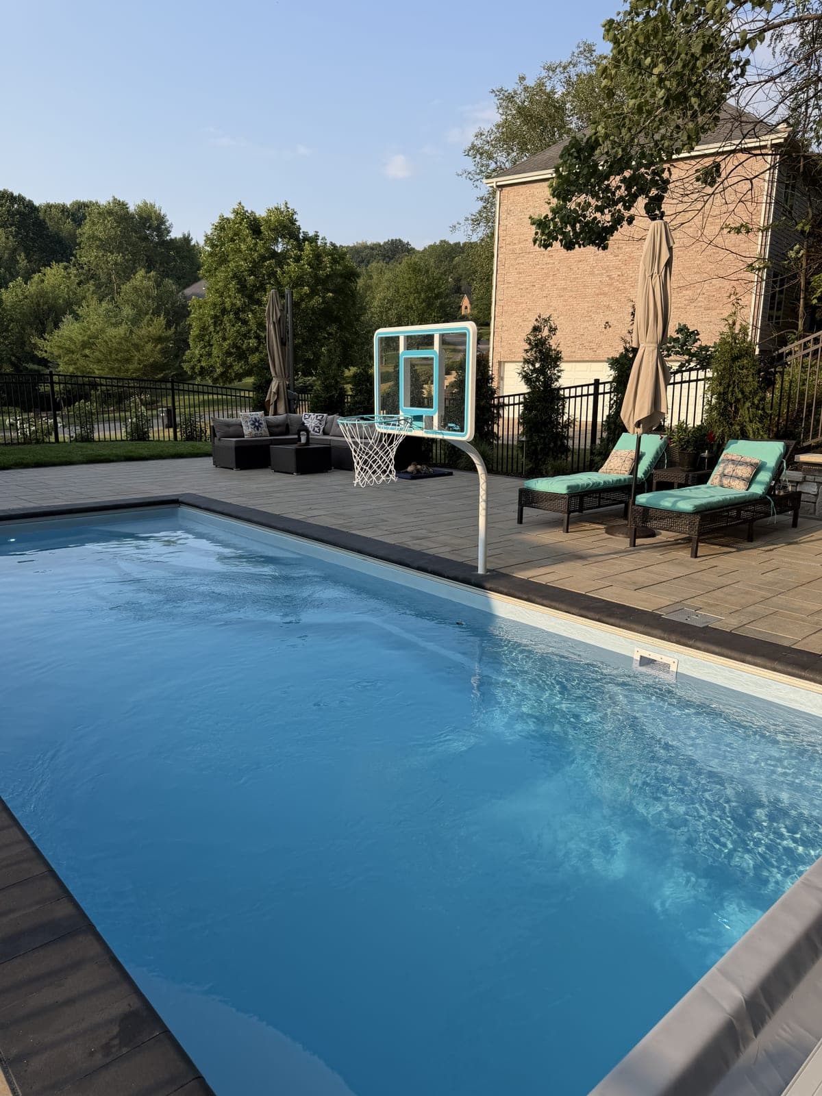 Inground pool with poolside basketball hoop and lounge chairs