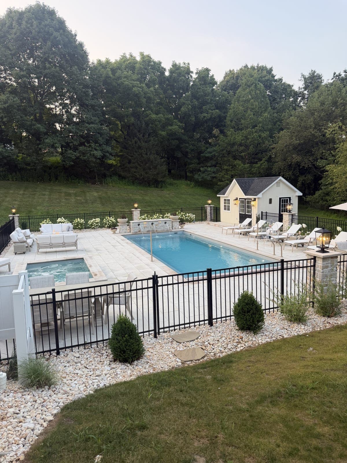 Pool, spa, lounge furniture and pool house at dusk