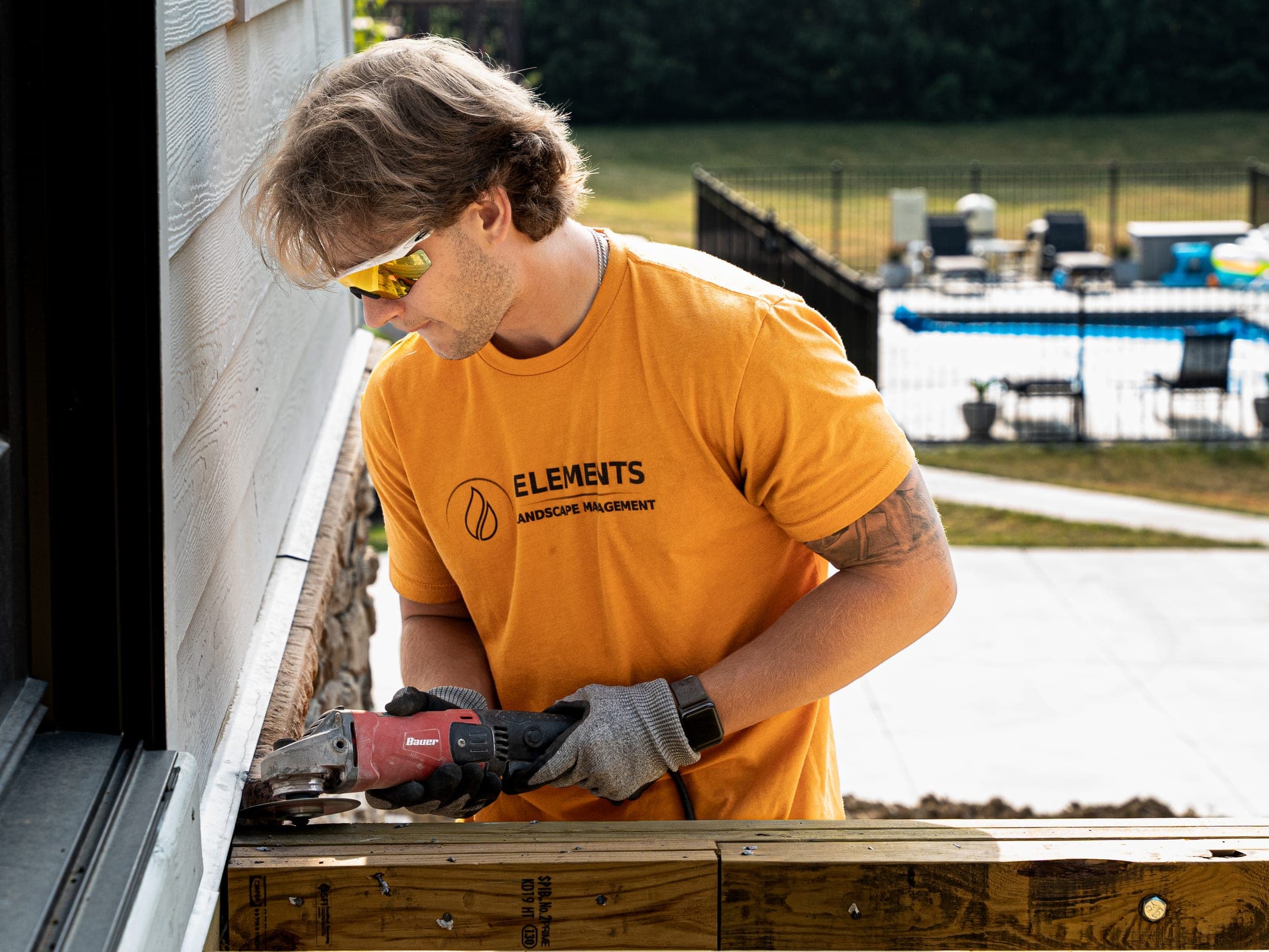 crew grinder deck framing poolside - Elements Landscape Management