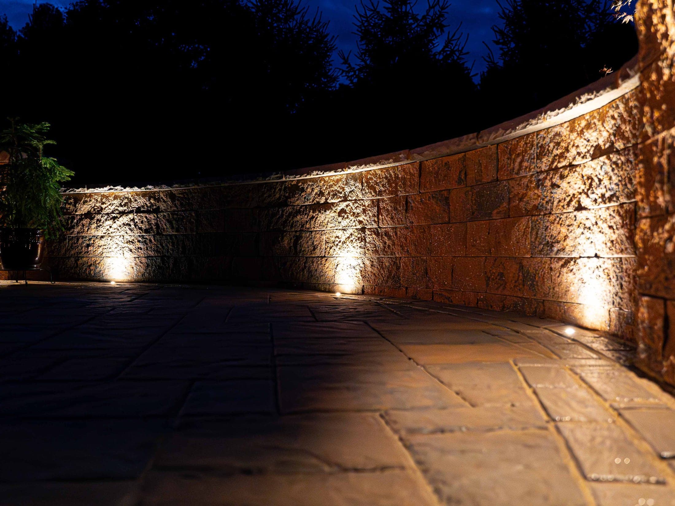Curved retaining wall lit with landscape lighting at night
