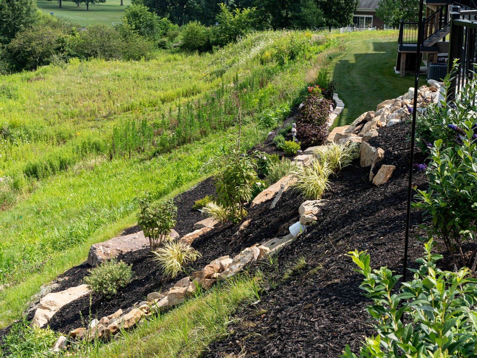 Layered boulder planting bed with mixed shrubs and perennials