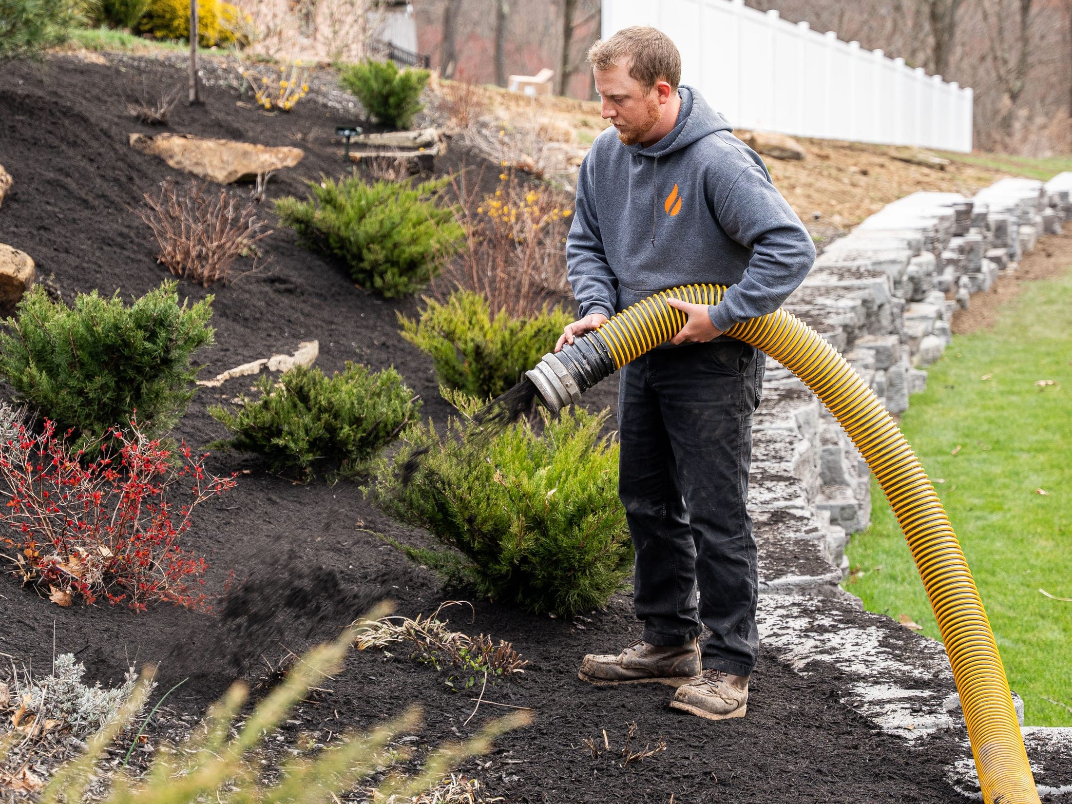 Hand-applied mulch bed along a landscape retaining wall