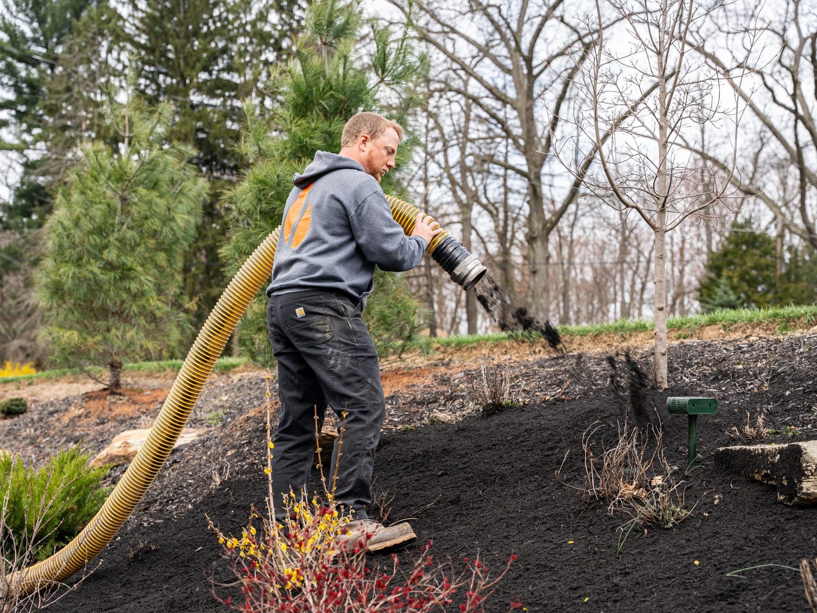 Crew blowing mulch into a terraced landscape bed with a FINN blower hose