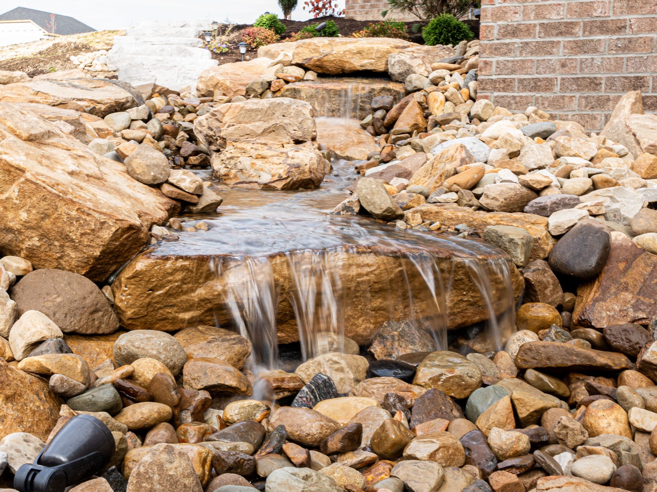 Multi-tier boulder waterfall built into a landscape bed