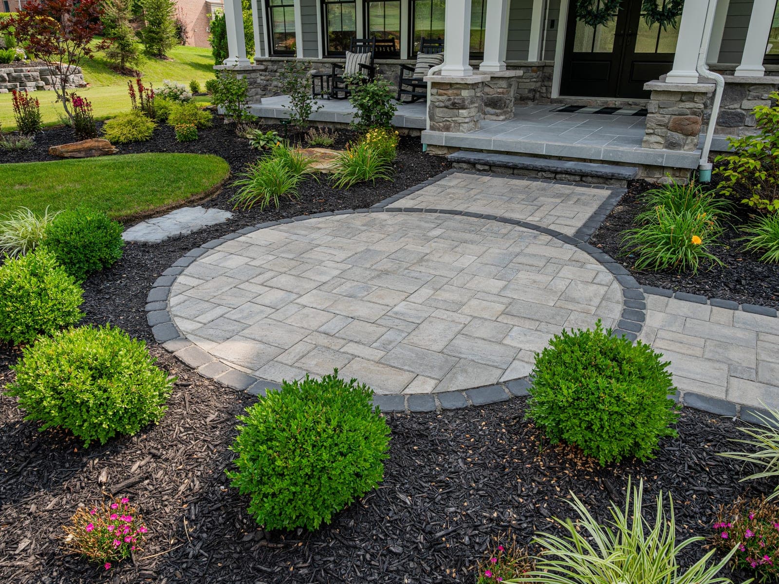 Ornamental grasses planted beside a driveway stone pillar
