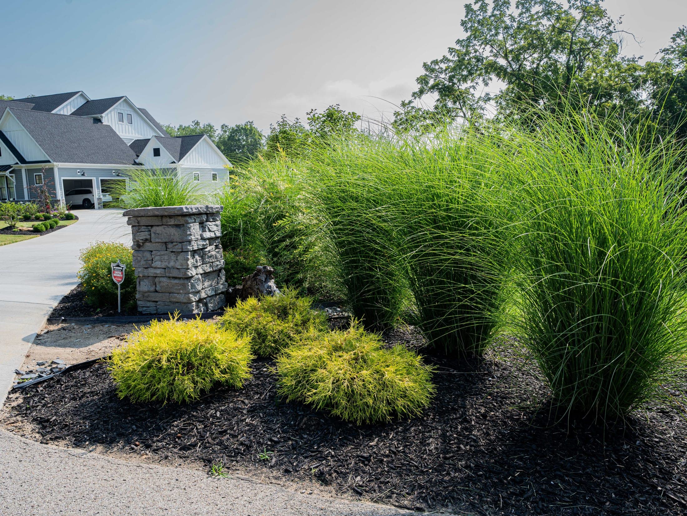 Ornamental grasses planted around a stone pillar