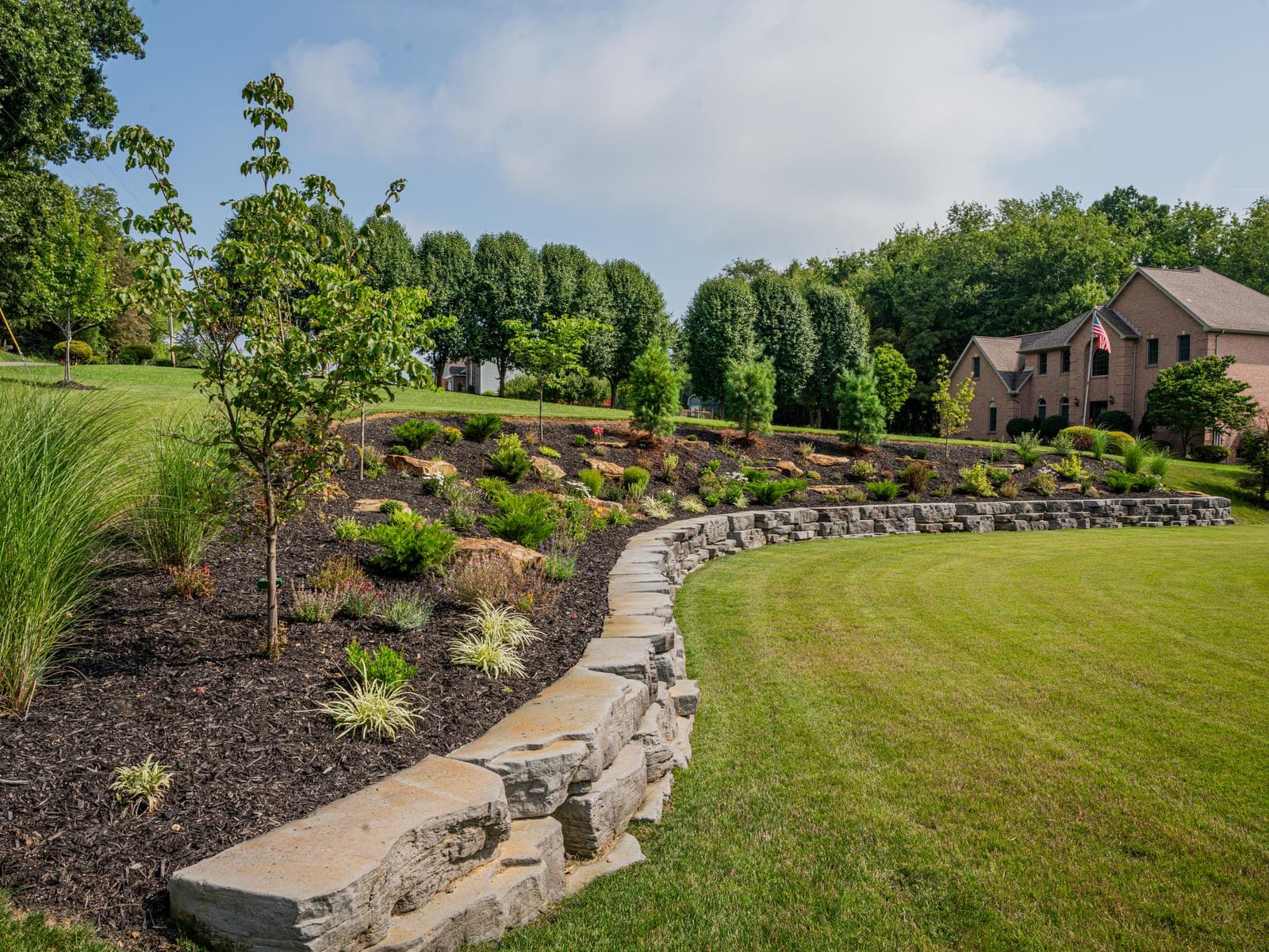 Entry flower bed wrapping a stone pillar