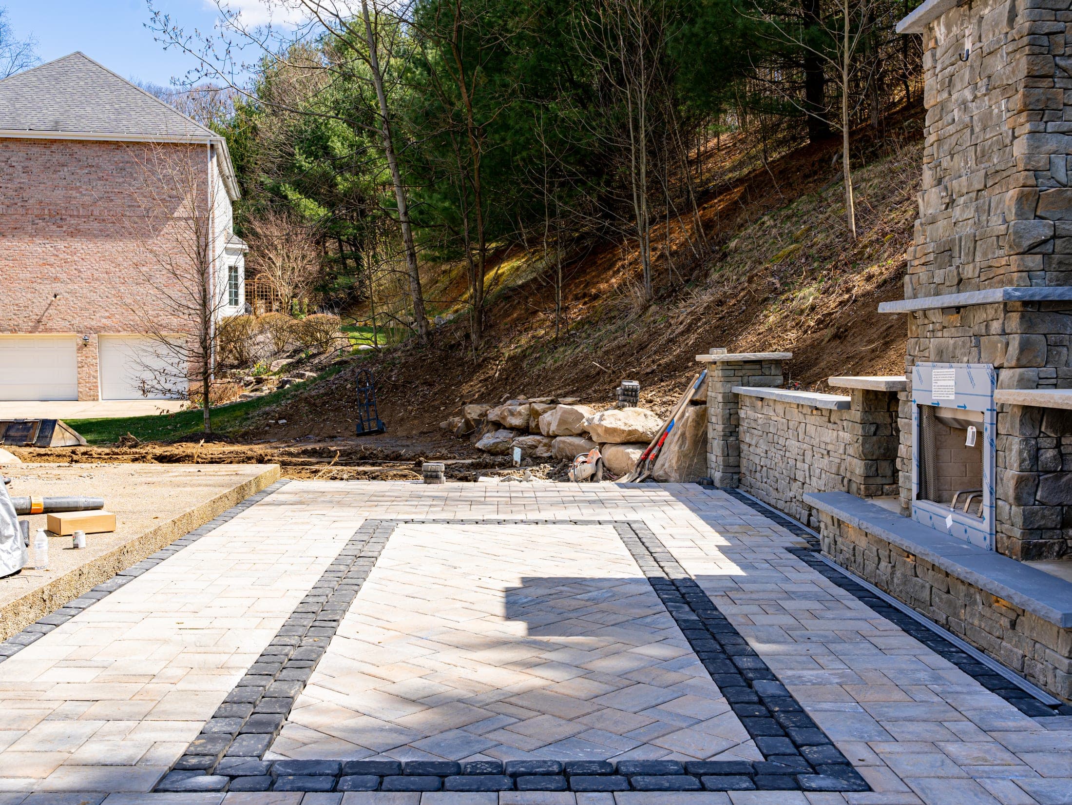 Paver patio with stone fireplace on a hillside