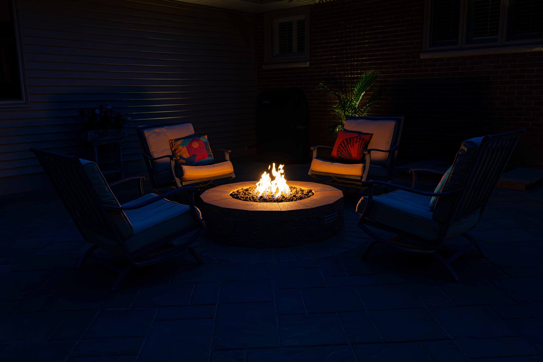 Round fire pit at night with hardscape lighting