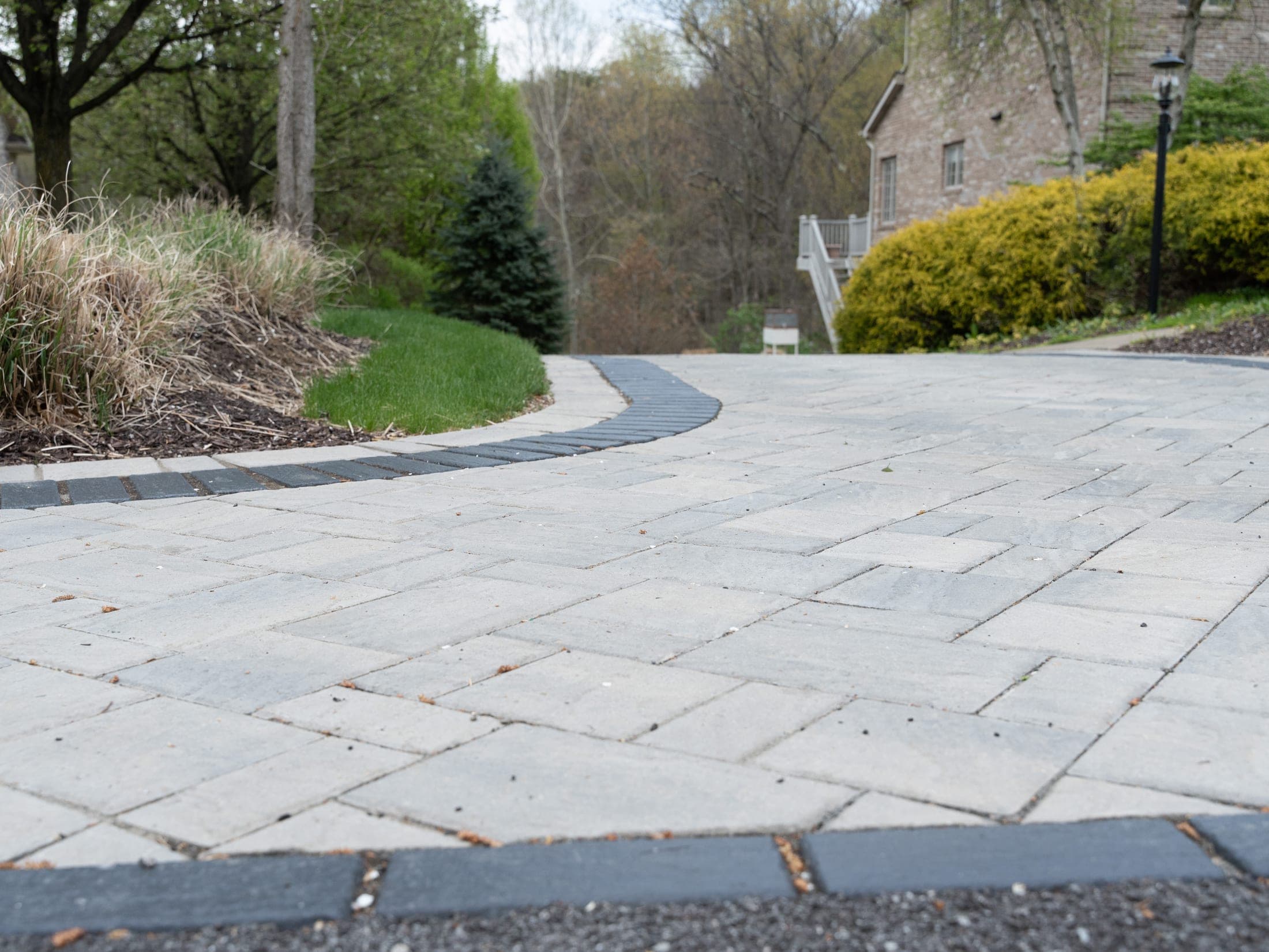 Paver driveway bordered by a landscape bed