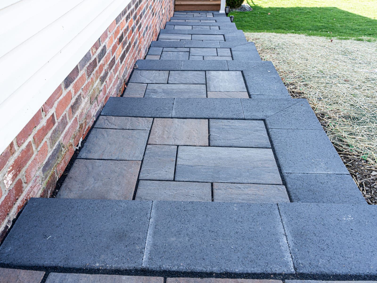 Two-tone paver walkway leading to a home entrance