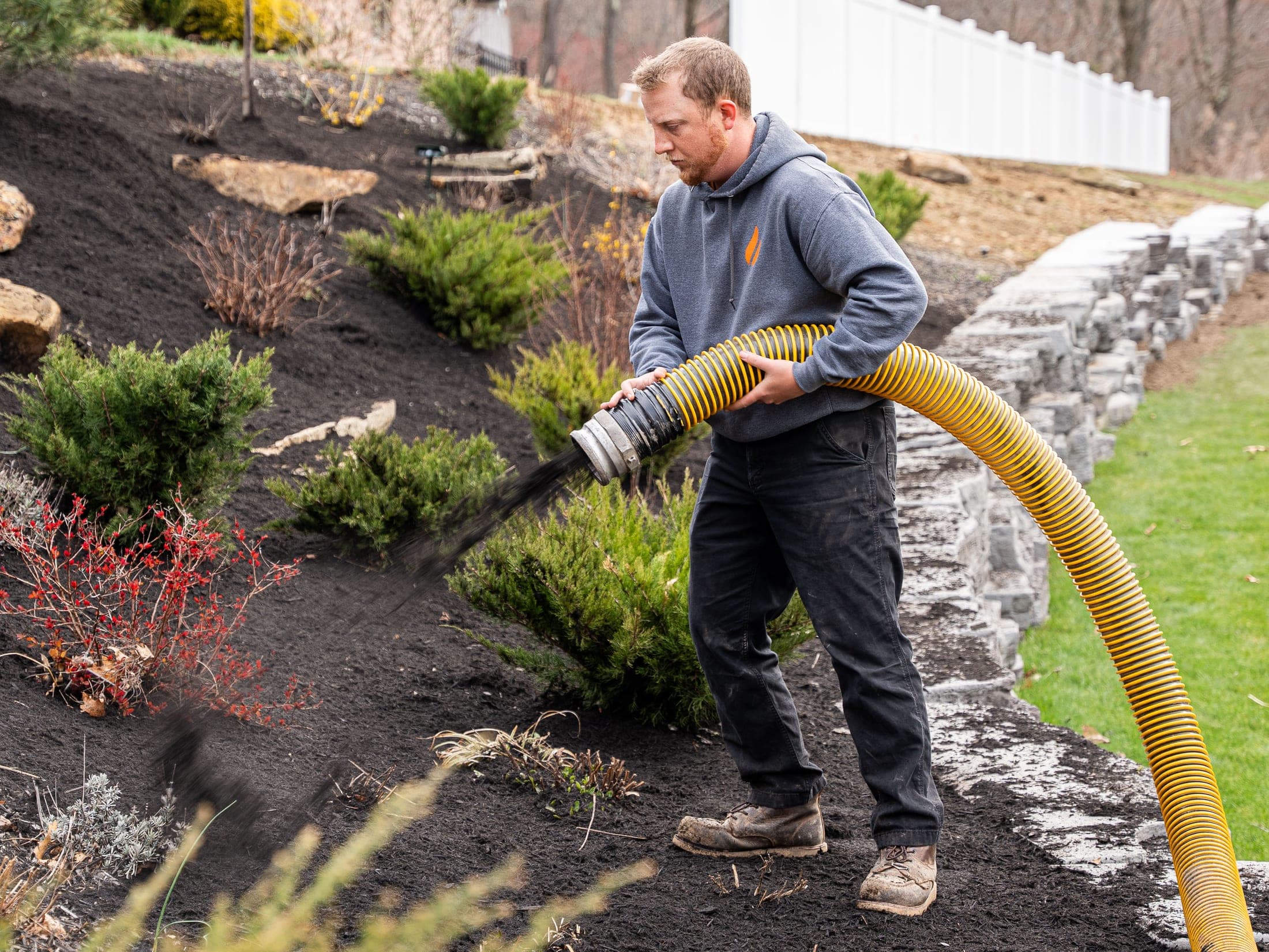 Mulch spraying out of a hose during a bed application