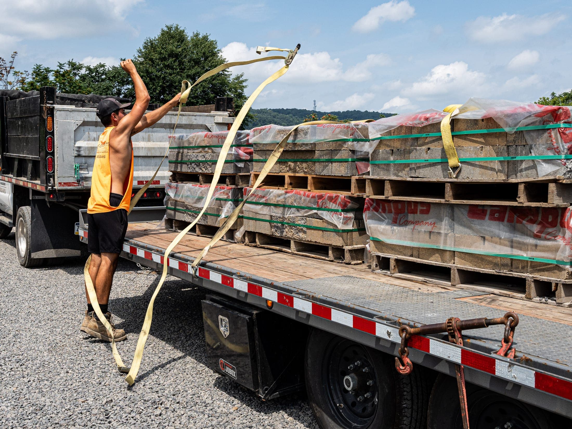 Elements crew strapping palletized pavers on a flatbed at the material yard