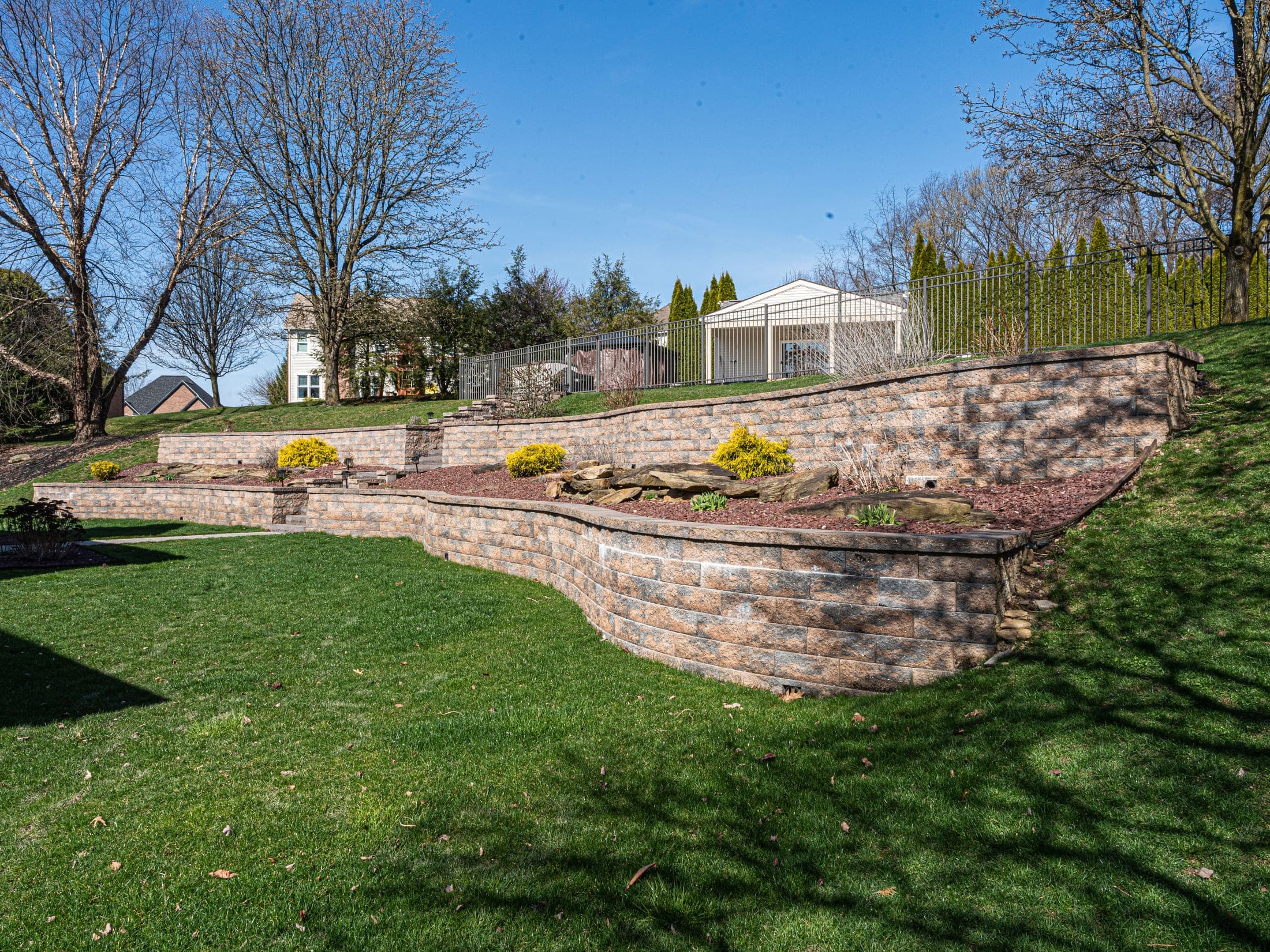 Sweeping tiered retaining wall across a hillside yard