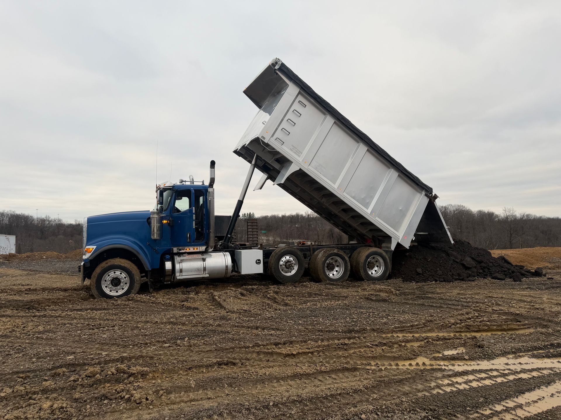 Triaxle dump truck unloading bulk material on a commercial job site
